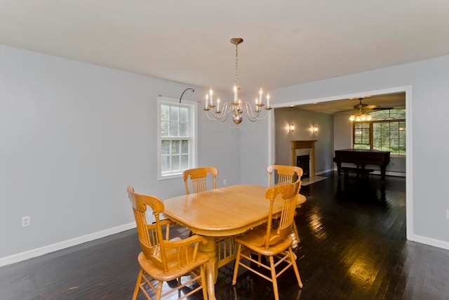 dining room with ceiling fan with notable chandelier and dark hardwood / wood-style flooring