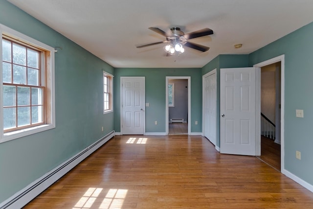 unfurnished bedroom featuring ceiling fan, baseboard heating, and light hardwood / wood-style flooring