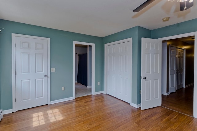 unfurnished bedroom with ceiling fan, hardwood / wood-style flooring, and a baseboard heating unit