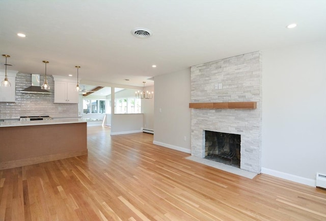 19 Woodcliff Rd, Holbrook, MA 02343 - unfurnished living room with a stone fireplace, light wood finished floors, baseboards, a chandelier, and baseboard heating