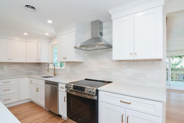 19 Woodcliff Rd, Holbrook, MA 02343 - kitchen featuring wall chimney range hood, stainless steel appliances, light wood-style flooring, a sink, and white cabinetry