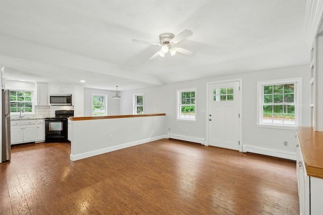 31 Granite St, Walpole, MA 02081 - unfurnished living room with a baseboard heating unit, dark wood-style flooring, a ceiling fan, and plenty of natural light