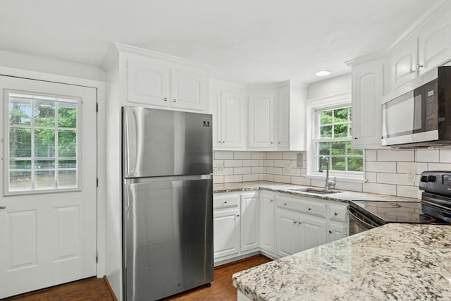 31 Granite St, Walpole, MA 02081 - kitchen featuring appliances with stainless steel finishes, light stone counters, white cabinetry, dark wood-style floors, and decorative backsplash