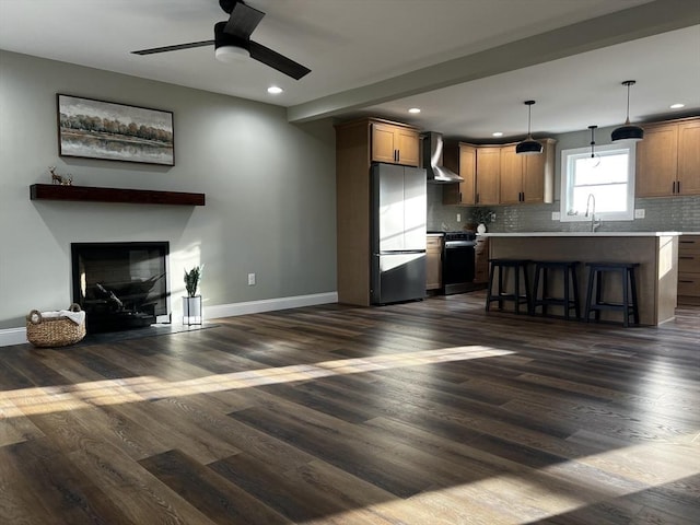 kitchen with a center island, stainless steel stove, fridge, wall chimney range hood, and decorative light fixtures