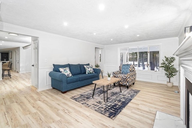 living room with crown molding, a textured ceiling, and light wood-type flooring