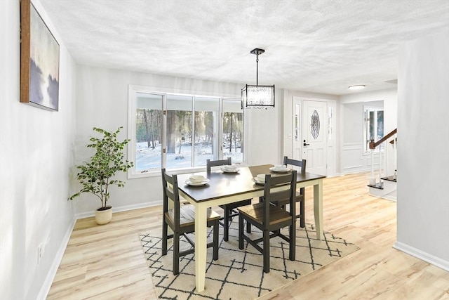 dining space featuring a notable chandelier, a textured ceiling, and light wood-type flooring