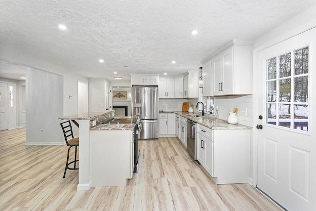 kitchen with sink, a breakfast bar area, a center island, stainless steel appliances, and white cabinets