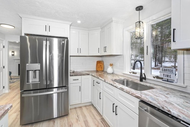 kitchen featuring sink, light stone counters, stainless steel appliances, decorative backsplash, and white cabinets