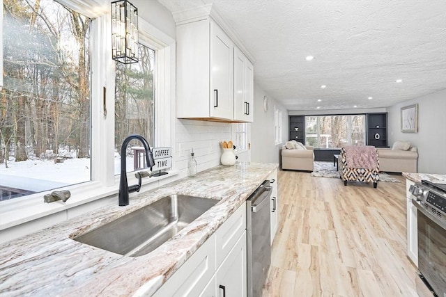 kitchen with light stone countertops, sink, white cabinets, and decorative light fixtures