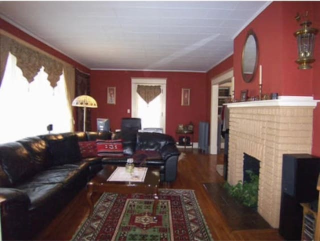 living room with a brick fireplace and dark hardwood / wood-style floors