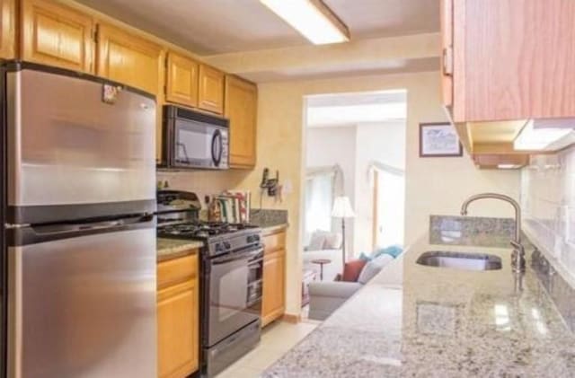 6 Tisdale Dr Unit 6, Dover, MA 02030 - kitchen with black appliances, light stone countertops, and light tile patterned floors