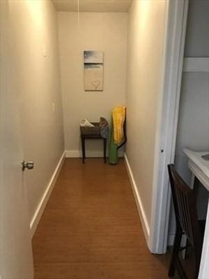 corridor featuring baseboards and wood finished floors