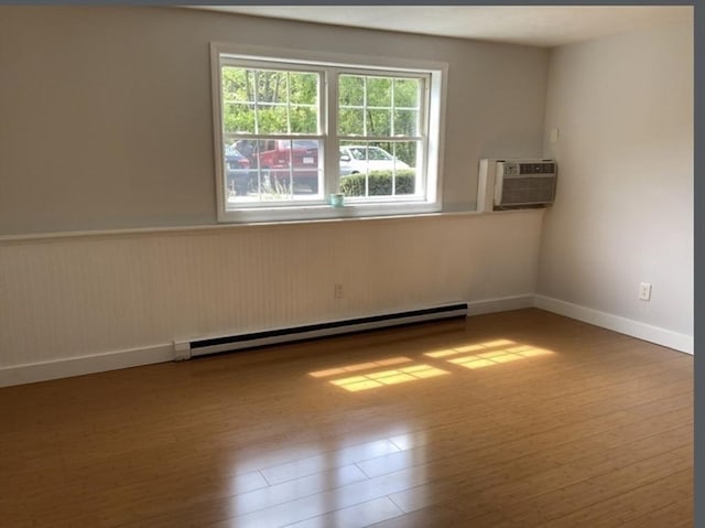 empty room with plenty of natural light, a baseboard radiator, and wood finished floors