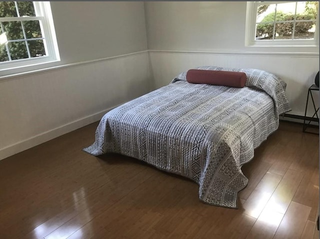 bedroom with baseboards, a baseboard radiator, and wood finished floors