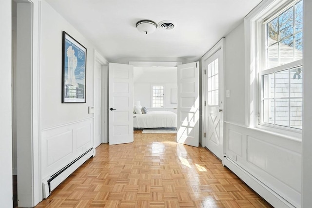 unfurnished bedroom featuring a decorative wall, a baseboard radiator, a baseboard heating unit, and visible vents
