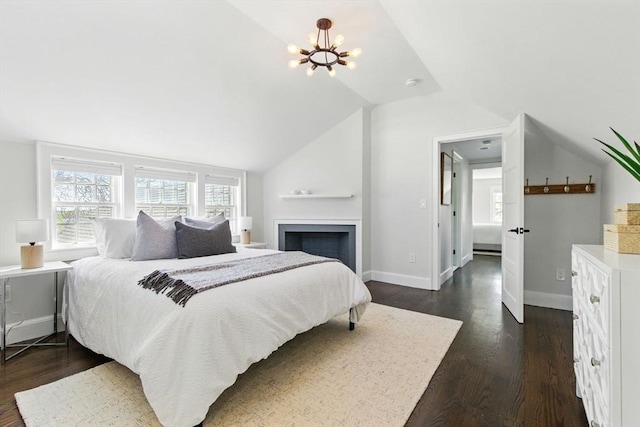 bedroom with a fireplace, baseboards, a chandelier, lofted ceiling, and dark wood-type flooring