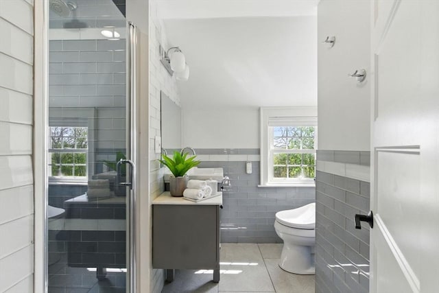 bathroom featuring toilet, tile walls, wainscoting, and tile patterned flooring