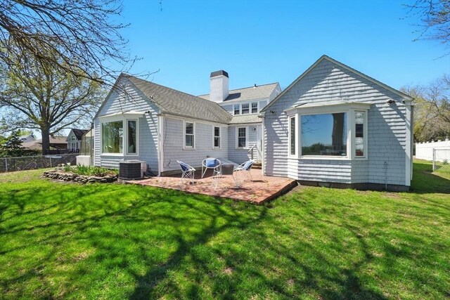back of property with fence, central AC unit, a chimney, a patio, and a yard
