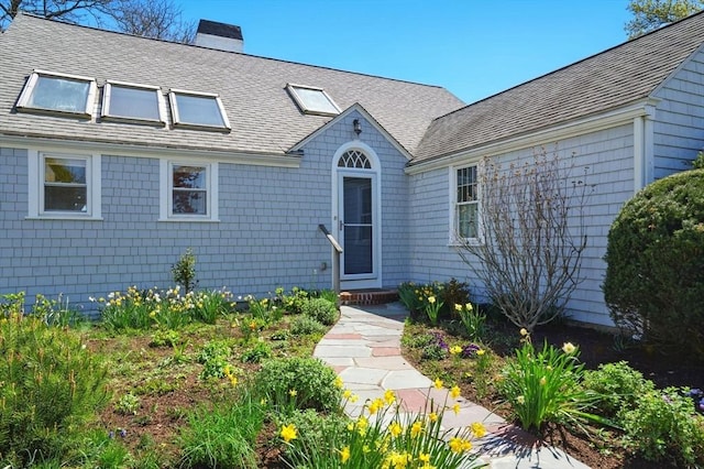 view of front of house featuring a chimney and roof with shingles