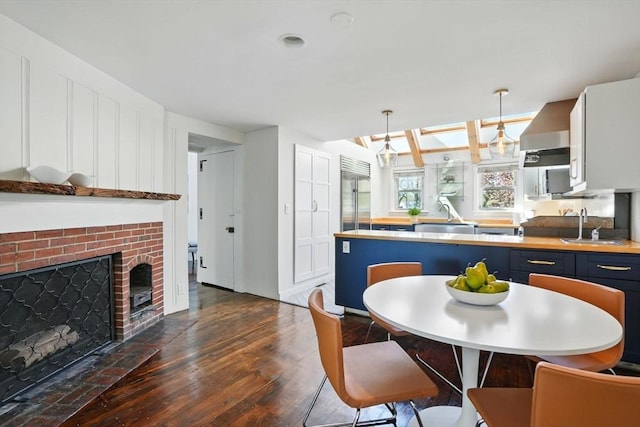 kitchen featuring a sink, dark wood finished floors, built in fridge, and pendant lighting