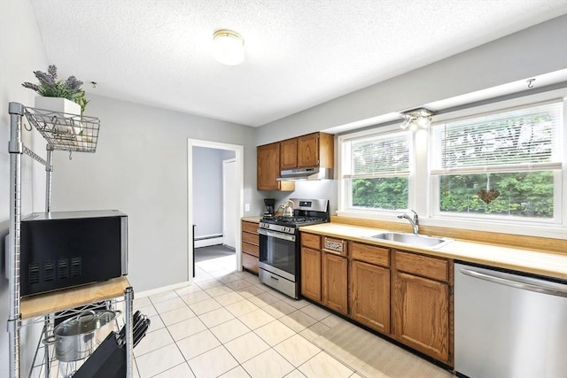 2500 Pendleton Ave Unit 2500, Chicopee, MA 01022 - kitchen with stainless steel appliances, under cabinet range hood, brown cabinetry, light countertops, and a textured ceiling