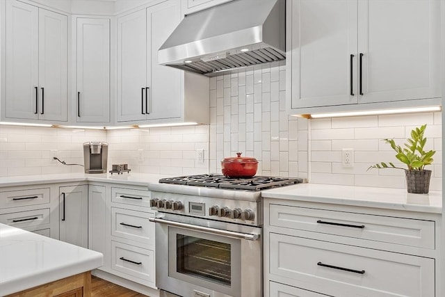 306 Laws Brook Rd, Concord, MA 01742 - kitchen featuring stainless steel range, wall chimney range hood, tasteful backsplash, and white cabinetry