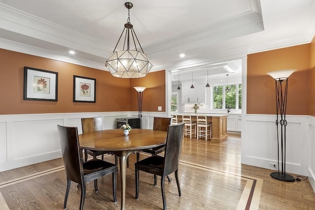 306 Laws Brook Rd, Concord, MA 01742 - dining space with a raised ceiling, ornamental molding, wainscoting, a decorative wall, and light wood-style flooring