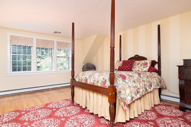 bedroom with a baseboard radiator and hardwood / wood-style floors