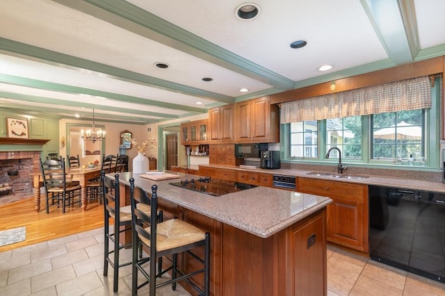 kitchen with pendant lighting, black appliances, a center island, sink, and beam ceiling