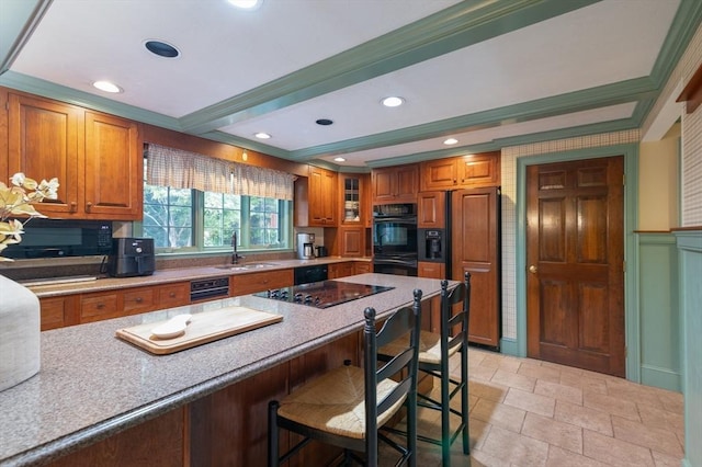 kitchen featuring sink, black appliances, a kitchen bar, and ornamental molding