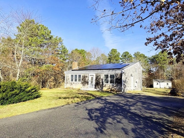 ranch-style home with solar panels, a shed, and a front yard