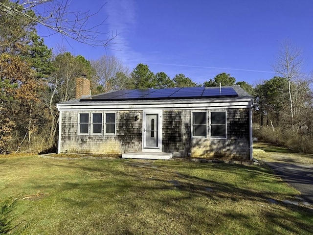 view of front of property with solar panels and a front lawn