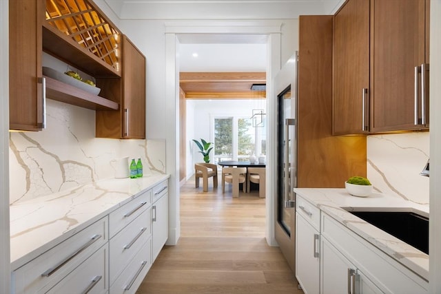 kitchen featuring light stone counters, backsplash, white cabinetry, and light hardwood / wood-style floors