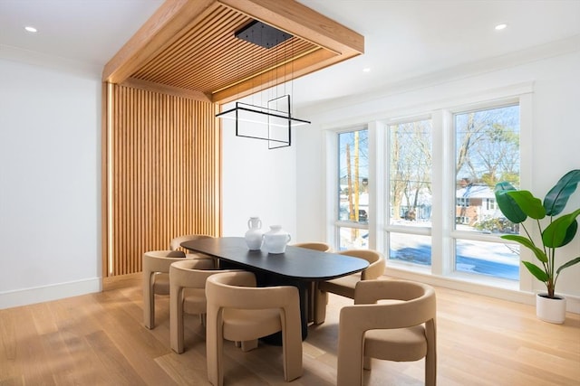 dining space with a wealth of natural light, light hardwood / wood-style flooring, ornamental molding, and an inviting chandelier