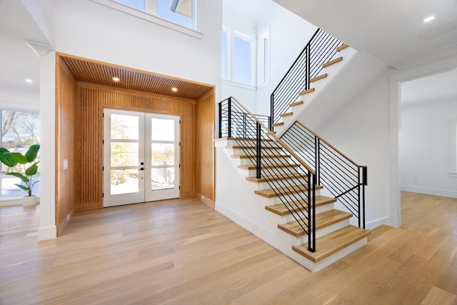 entryway featuring wood walls, light hardwood / wood-style floors, and french doors