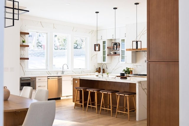 kitchen with white cabinets, a breakfast bar, light hardwood / wood-style floors, and stainless steel appliances