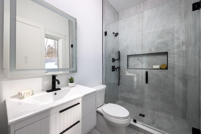 bathroom with toilet, a shower with door, and vanity