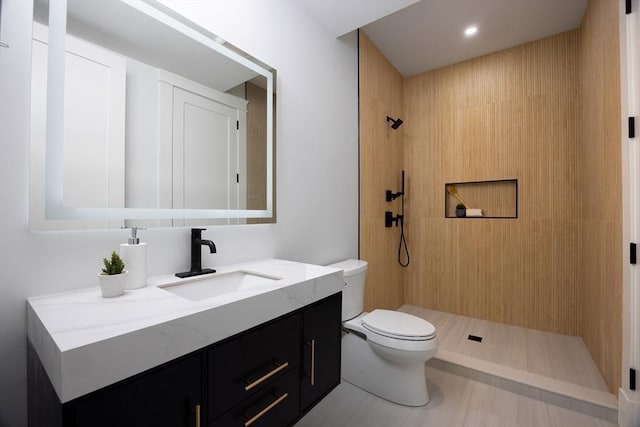 bathroom featuring tiled shower, toilet, and vanity