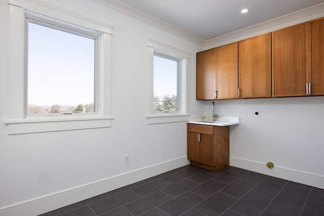 clothes washing area featuring electric dryer hookup, a healthy amount of sunlight, and cabinets