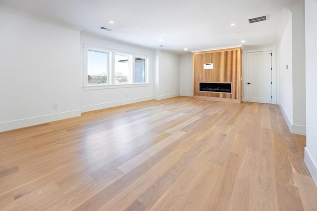 unfurnished living room with crown molding, light hardwood / wood-style floors, and a fireplace