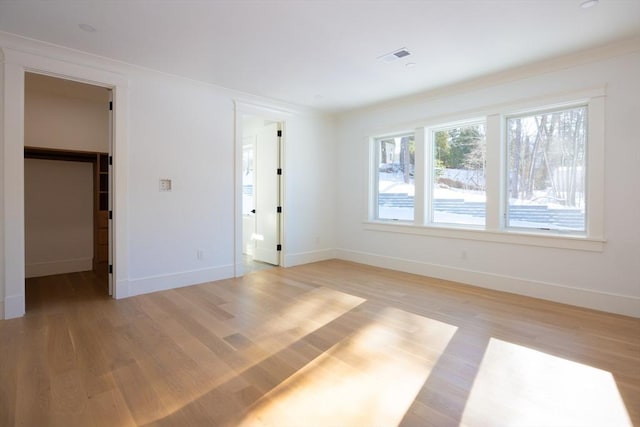 empty room with light hardwood / wood-style floors and ornamental molding