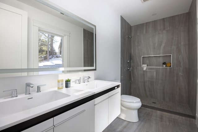 bathroom featuring a tile shower, toilet, and vanity