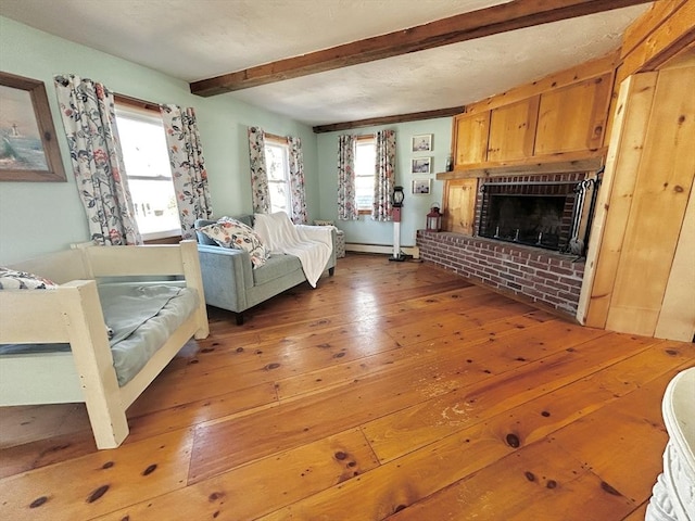 living area featuring beam ceiling, a baseboard radiator, a fireplace, and wood-type flooring