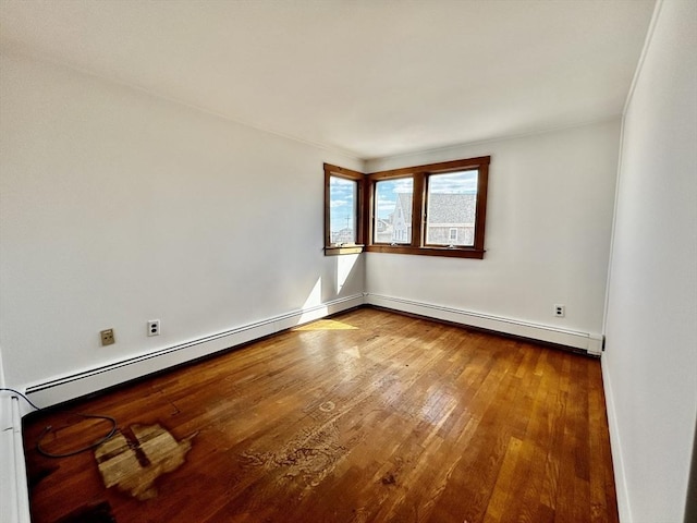 spare room featuring hardwood / wood-style floors, baseboards, and a baseboard radiator