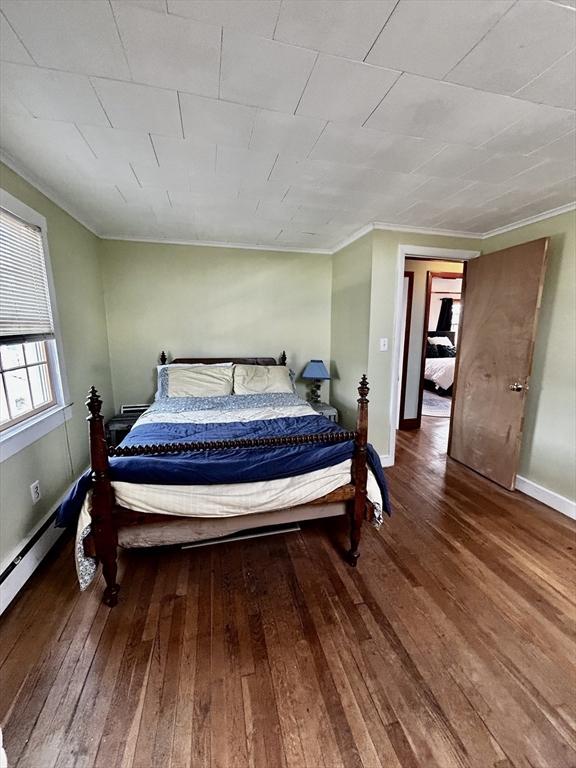 bedroom featuring baseboards, wood-type flooring, and crown molding