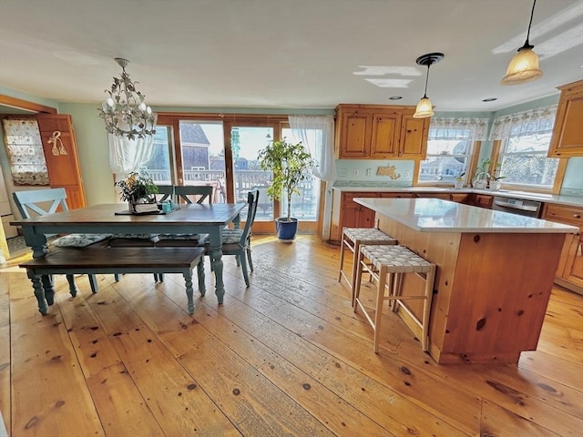 kitchen featuring light countertops, light wood-style floors, dishwasher, brown cabinets, and a center island