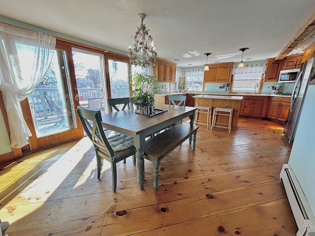 dining space with a baseboard heating unit, light wood-style floors, and a notable chandelier