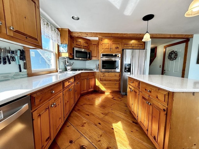 kitchen featuring brown cabinetry, appliances with stainless steel finishes, light wood-type flooring, and decorative light fixtures