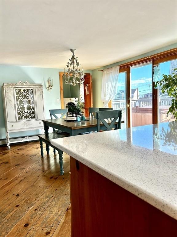 interior space featuring a notable chandelier, washer / dryer, a baseboard heating unit, and hardwood / wood-style floors