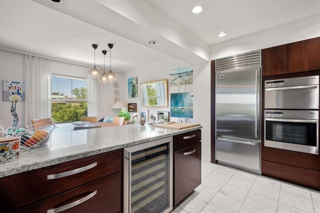 416 Commonwealth Ave Unit 504, Boston, MA 02215 - kitchen with beverage cooler, stainless steel appliances, light stone counters, dark brown cabinetry, and decorative light fixtures